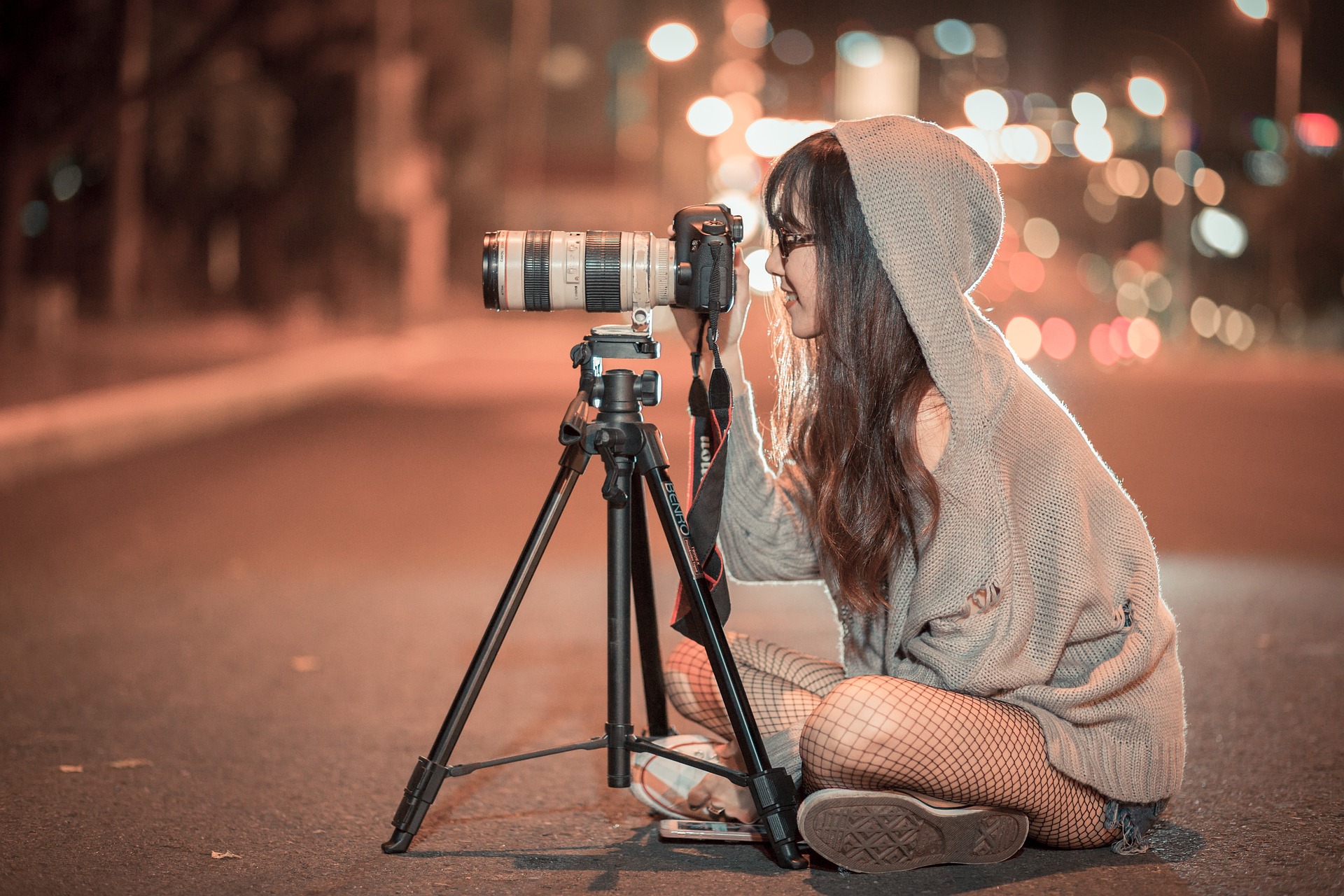 Junge alterantive Frau mit profesioneller Kamera in der Stadt bei Nacht